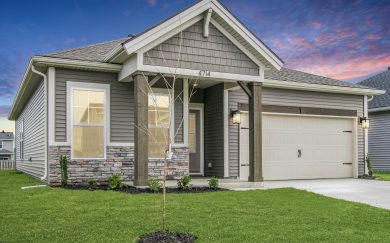 Exterior front view of the Leonardo Craftsman home at sunset, featuring a combination of stone and siding, decorative cedar columns, and a two-car garage.