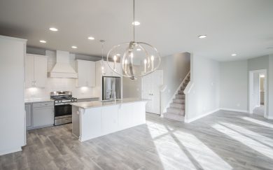 Kitchen w/ Deluxe Features | Dining Area | Family Room | Stairs to Bonus Deluxe Features kitchen layout in the Emory Craftsman floor plan by Jagoe Homes, featuring deluxe features, a view of the family room, owners suite, and staircase leading to the bonus room