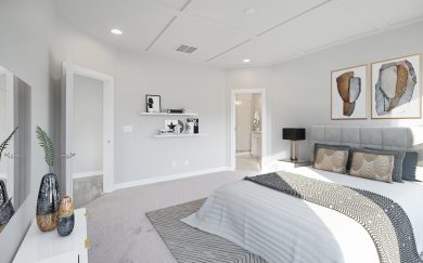 Owner's Suite Owner’s Suite in the Emory Craftsman floor plan by Jagoe Homes, showcasing an optional coffered ceiling detail, large windows for natural light, and an open view into the Owner’s Bath with a modern vanity and tiled showe
