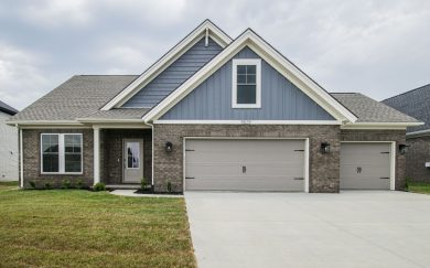 Front exterior of the Little Rock Craftsman home, featuring a combination of brick and blue vertical siding, three-car garage, gabled rooflines, and a covered front entry with a glass door.