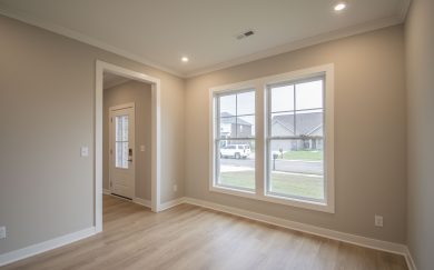 A front room with large double windows, Revwood flooring, and LED lighting, offering a bright view of the street outside.