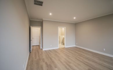 Owner&rsquo;s bedroom with neutral tones, Revwood flooring, LED lighting, and direct access to the en-suite bathroom and walk-in closet.