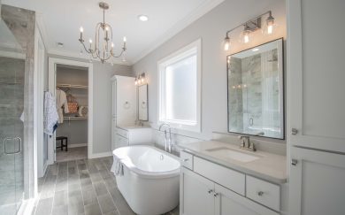 Elegant primary bathroom with a freestanding soaking tub, dual vanities, a walk-in tile shower, and a spacious walk-in closet.