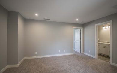 Carpeted upstairs loft area with LED lighting, connected to a hallway and full bathroom, featuring neutral gray walls and white trim.