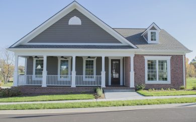 Merlot Front exterior of the Merlot floor plan, featuring a charming craftsman design with a large covered porch, brick accents, and a gable roof. White columns and trim contrast beautifully with the rich siding, creating inviting curb appeal.