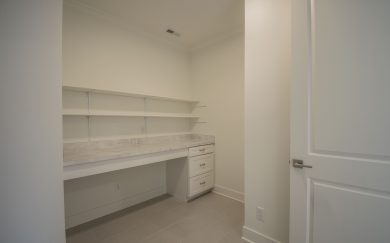 Laundry Room Dedicated laundry room with built-in countertop, drawers, and open shelving, offering ample workspace and storage.