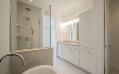 Owner's Bath Owner’s bathroom with a frameless glass walk-in shower, freestanding soaking tub, and double vanity with white cabinetry and quartz countertops.