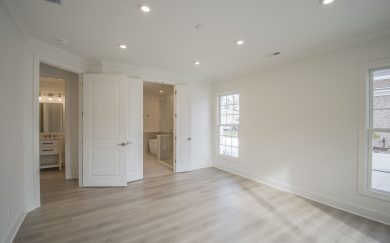 Owner's Suite Owner’s suite with Revwood flooring, large windows, and double doors opening to a spacious en-suite bath featuring a walk-in shower and soaking tub.