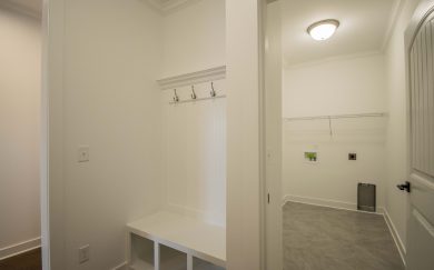 Drop zone area in the Emory Craftsman home featuring a built-in bench with cubbies and coat hooks, adjacent to a spacious laundry room with tile flooring and utility hookups.