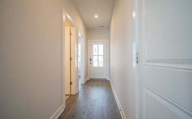 Interior view of the front entryway in the Leonardo Craftsman home, featuring a glass-paneled door, Revwood flooring, and access to side rooms.