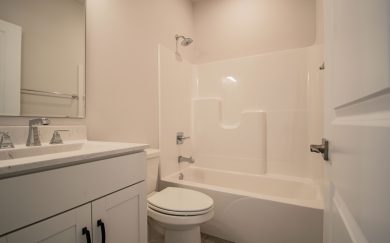 Full bathroom in the Leonardo Craftsman featuring a white vanity with chrome fixtures, integrated sink, and a tub/shower combination with molded shelving.
