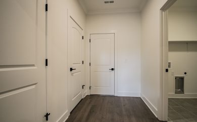 Family Entry | Laundry Room Family Entry with storage, leading to the laundry room and other utility spaces, featuring Revwood flooring and white trim.