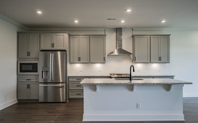 Deluxe Kitchen Deluxe kitchen with gray cabinetry, white subway tile backsplash, stainless steel appliances, granite countertops, and a central island with a matte black faucet.