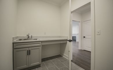Laundry Room with Deluxe Features Deluxe Laundry room with a drop-in sink, base cabinet storage, extended folding counter, and tile flooring.