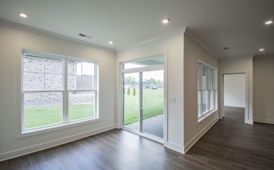 Dining Area | Covered Patio Bright space with large windows and a sliding glass door leading to a covered patio, showcasing a view of the backyard and neighboring homes.