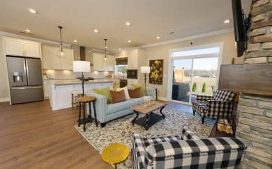 Upgraded Layout w/ Deluxe Features Kitchen | Great Room Upgraded layout featuring a deluxe kitchen with granite countertops, soft-close cabinetry, and a Great Room with an electric fireplace with floor-to-ceiling stone in the Carolina Craftsman floor plan by Jagoe Homes.