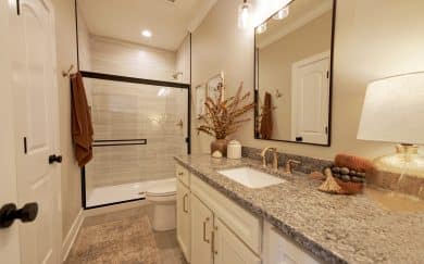 Expanded Bath 2 Expanded Bath 2 in the Carolina Craftsman floor plan by Jagoe Homes, featuring granite countertops, a ceramic walk-in shower, and linen closet with MDF shelving.